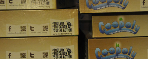 Stacks of Co-opoly boxes waiting to hit the social justice assembly line