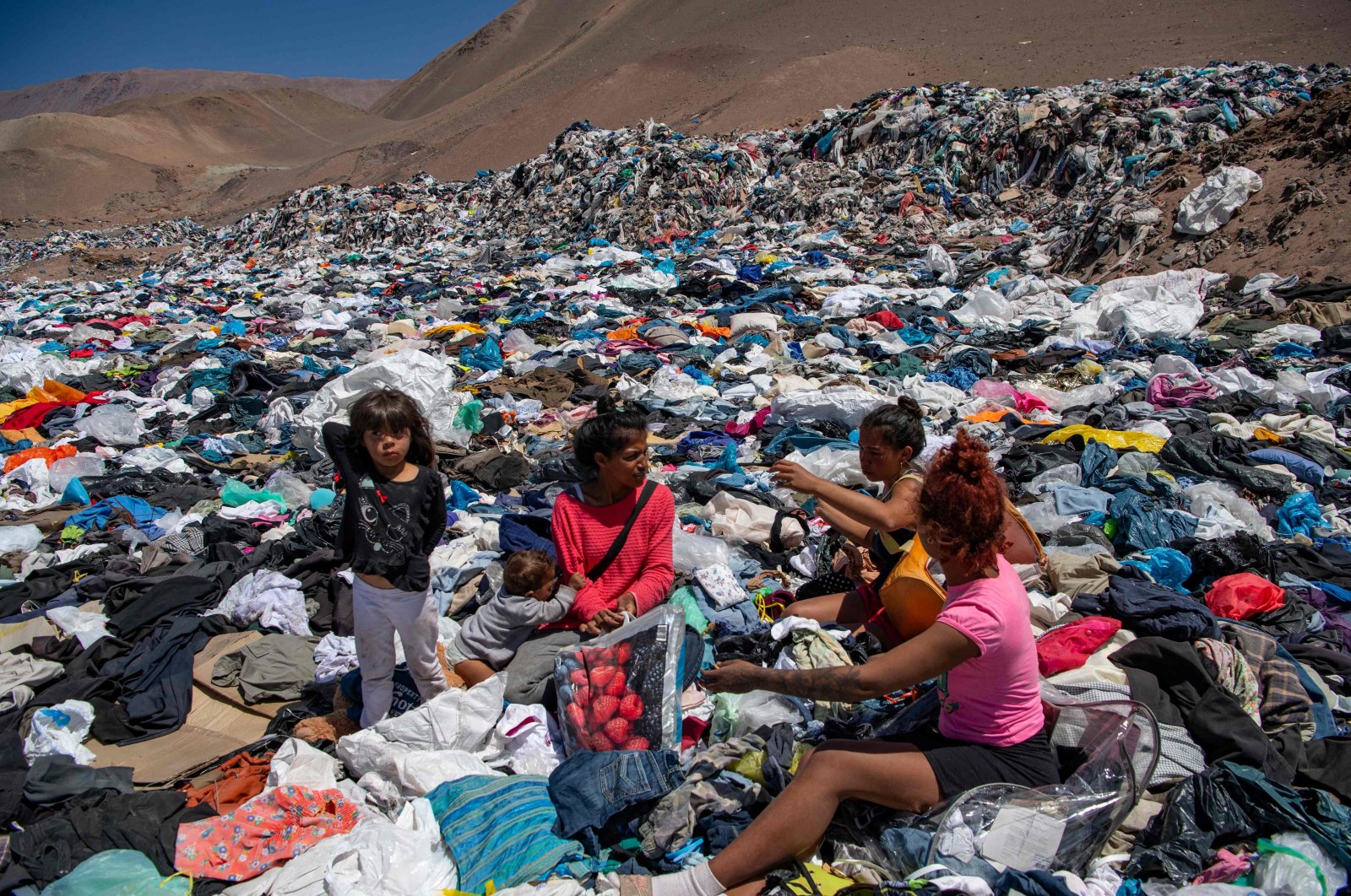 Women from <span style="font-weight: 400;">Alto Hospicio</span> search for salvageable used clothing amid the piles of waste. Credit: Agence France-Presse