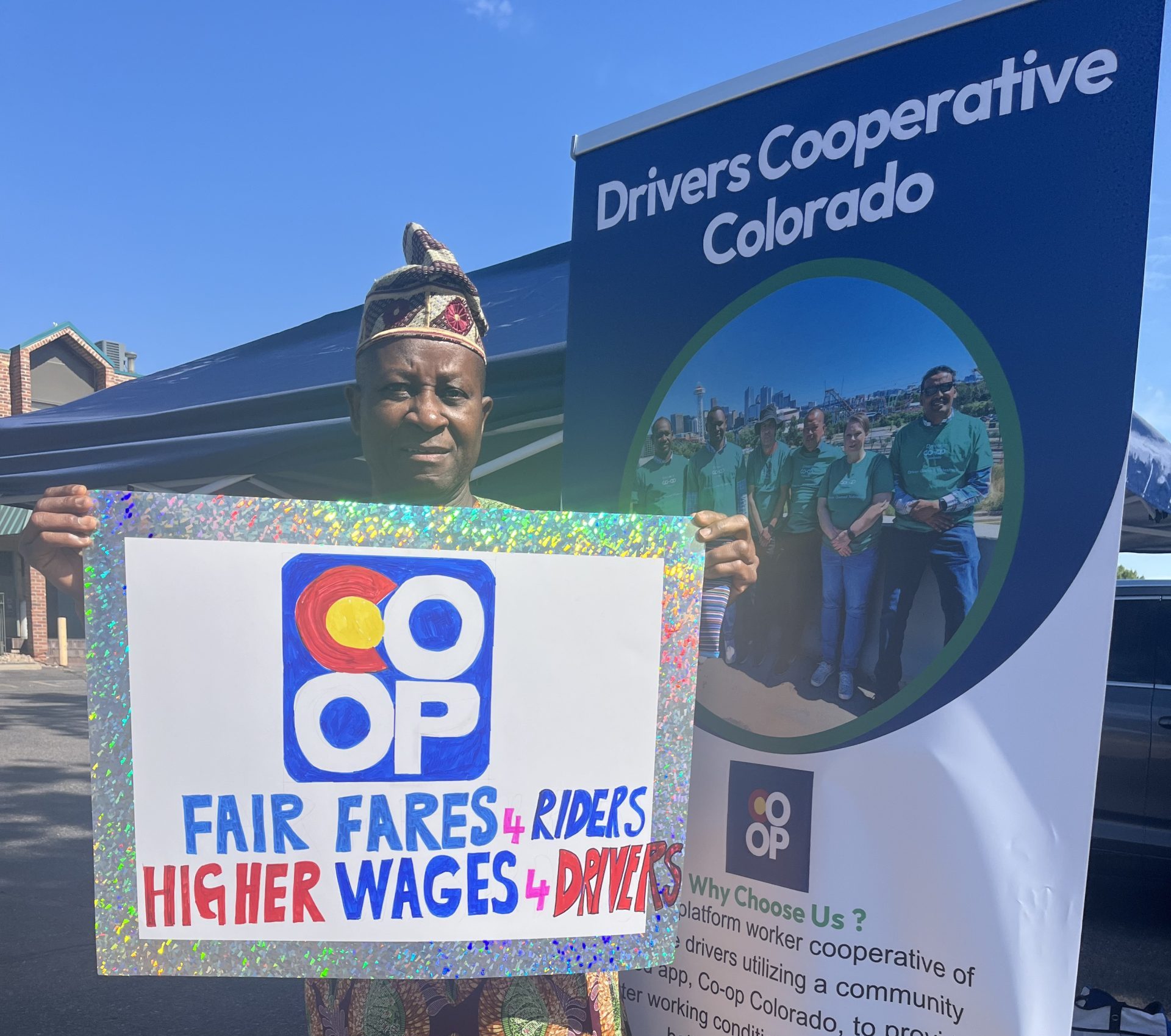 Member-driver with sign reading, "fair wages for rides, higher wages for drivers."